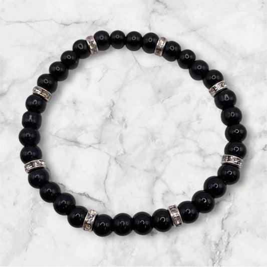 Svart pärlarmband med vita strasstenar.