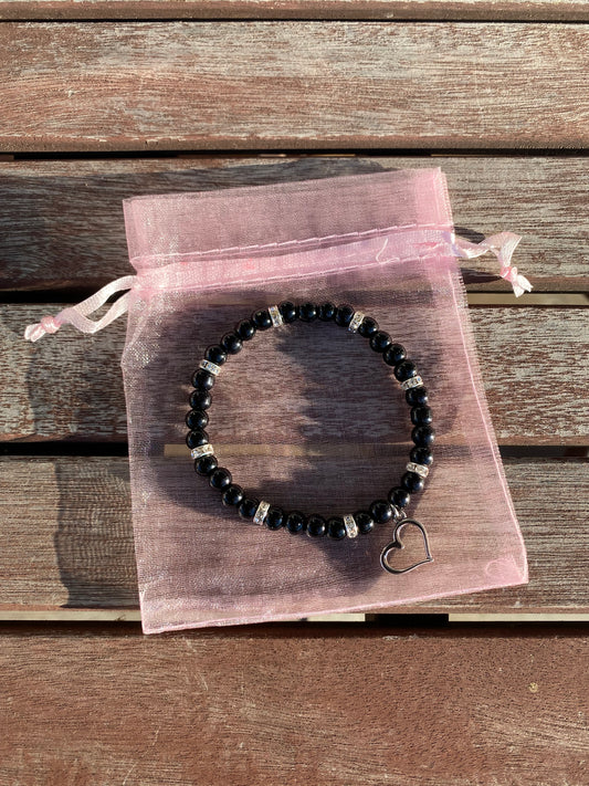 Svart pärlarmband med silverfärgad hjärtberlock och vita strasstenar