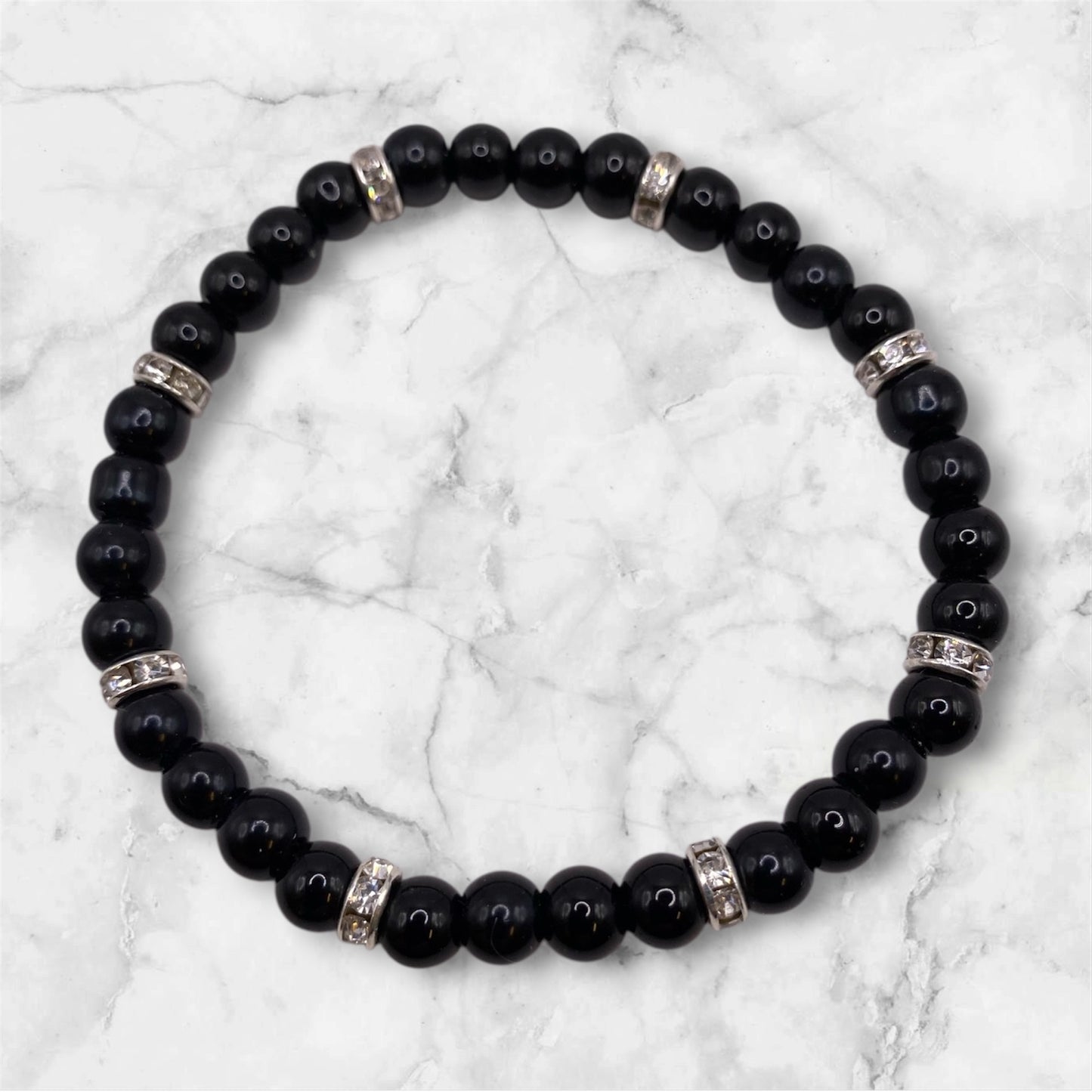 Svart pärlarmband med vita strasstenar.