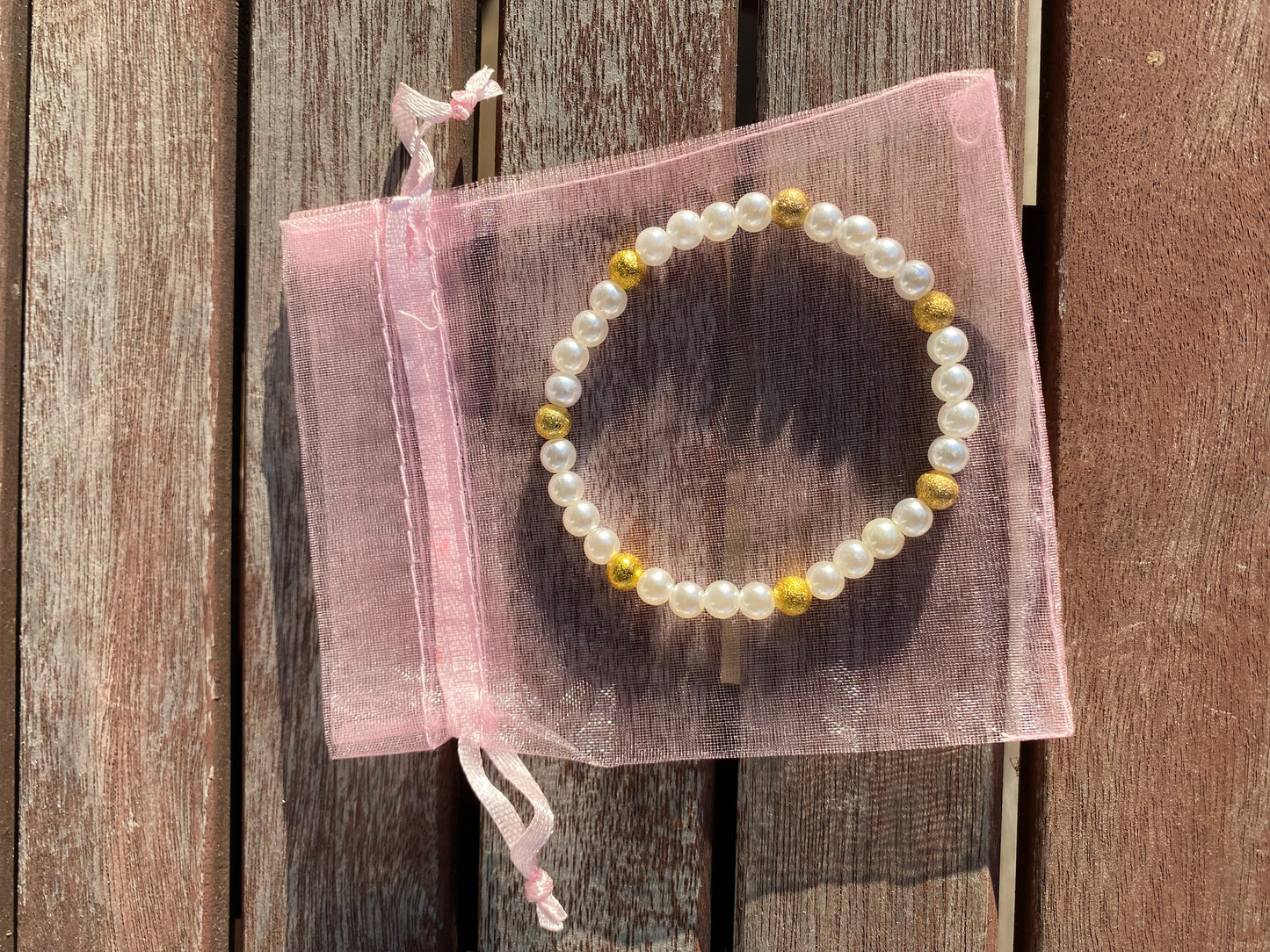 Pärlarmband med vita glaspärlor och guldfärgade  stardustpärlor