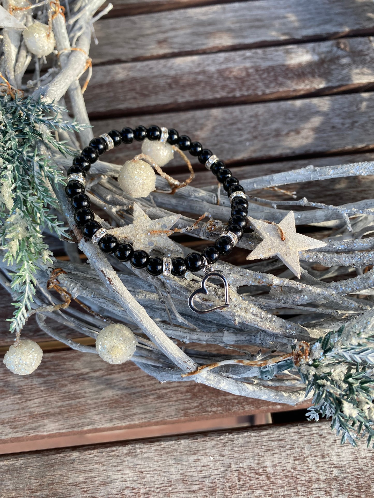 Svart pärlarmband med silverfärgad hjärtberlock och vita strasstenar