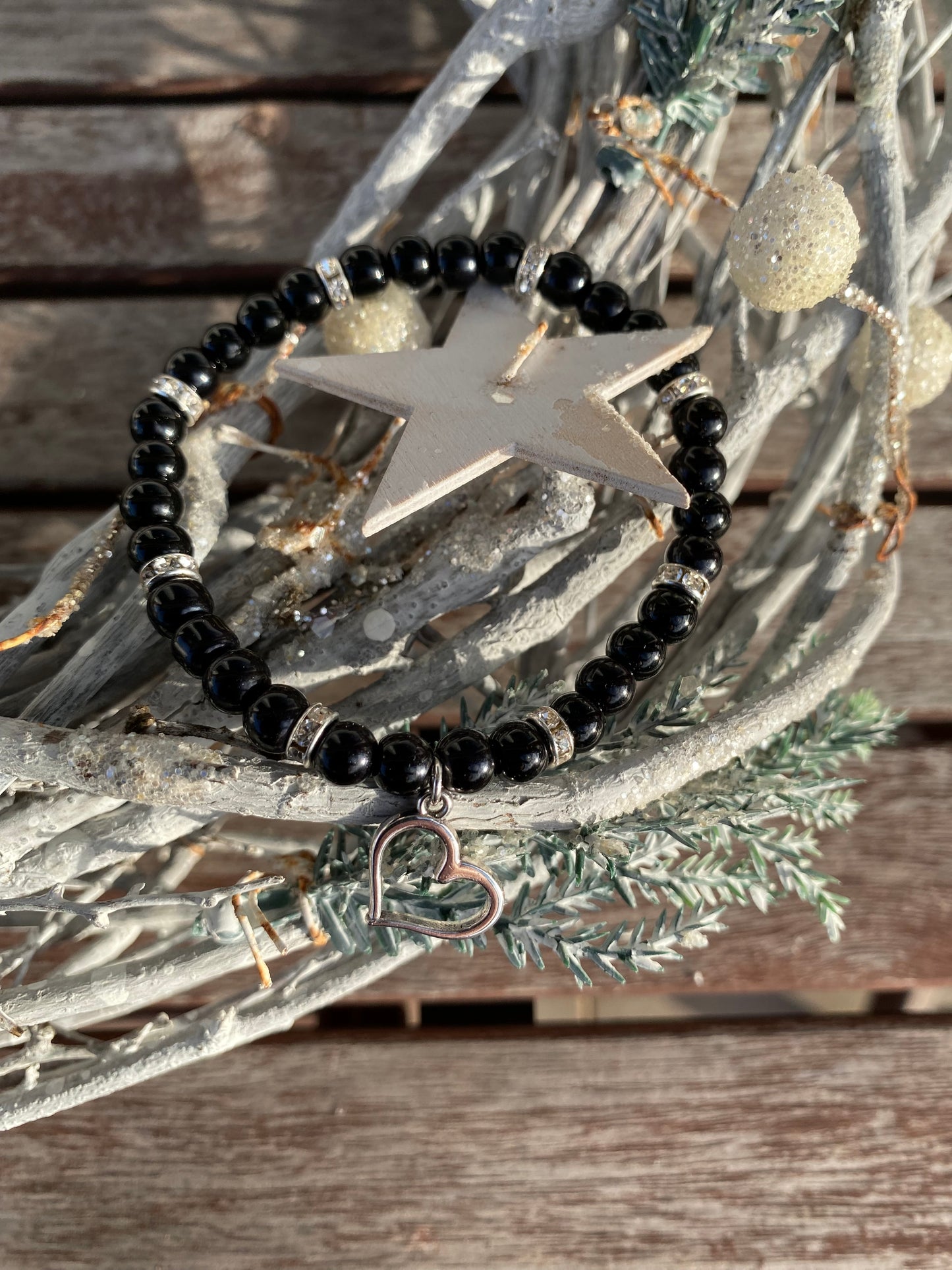 Svart pärlarmband med silverfärgad hjärtberlock och vita strasstenar