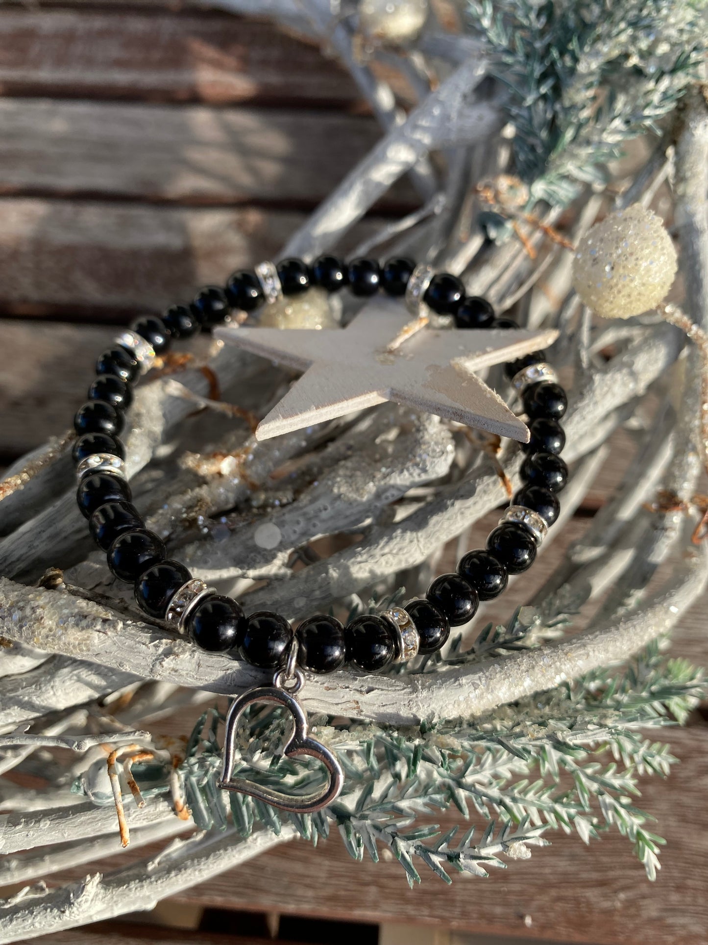 Svart pärlarmband med silverfärgad hjärtberlock och vita strasstenar