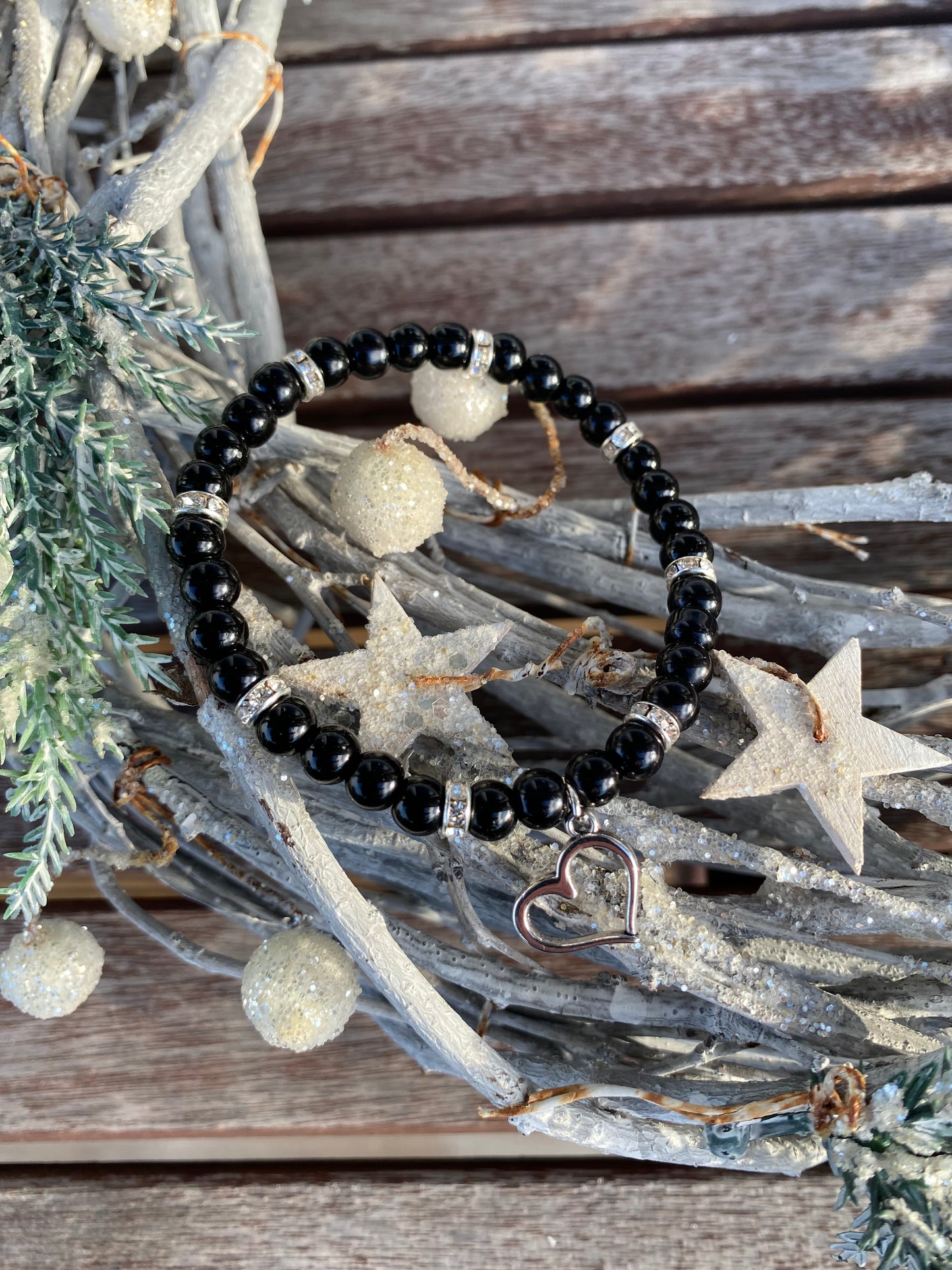 Svart pärlarmband med silverfärgad hjärtberlock och vita strasstenar