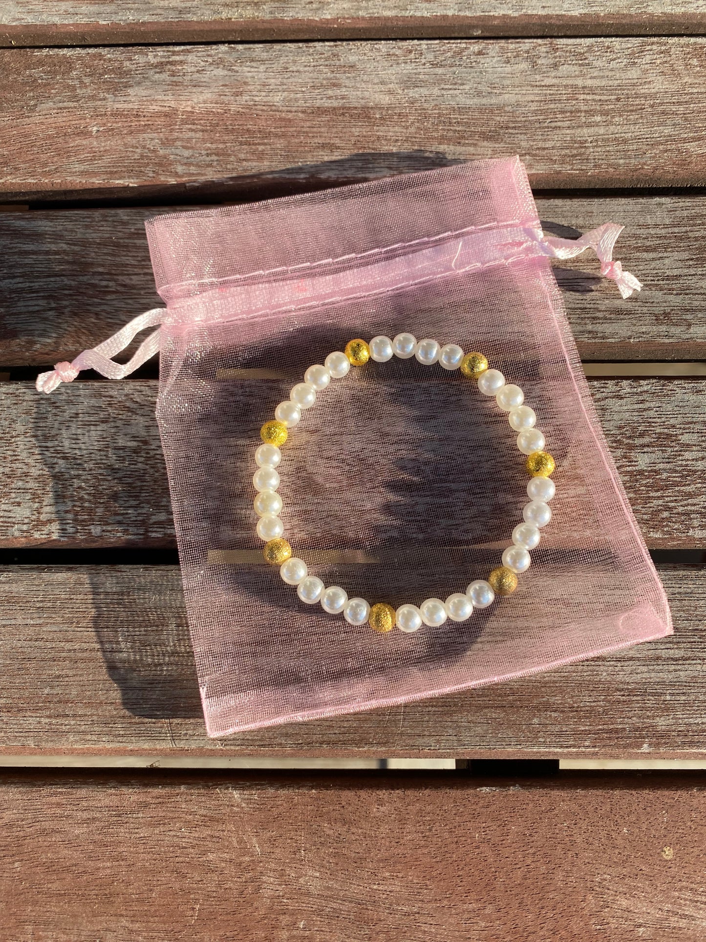 Pärlarmband med vita glaspärlor och guldfärgade  stardustpärlor